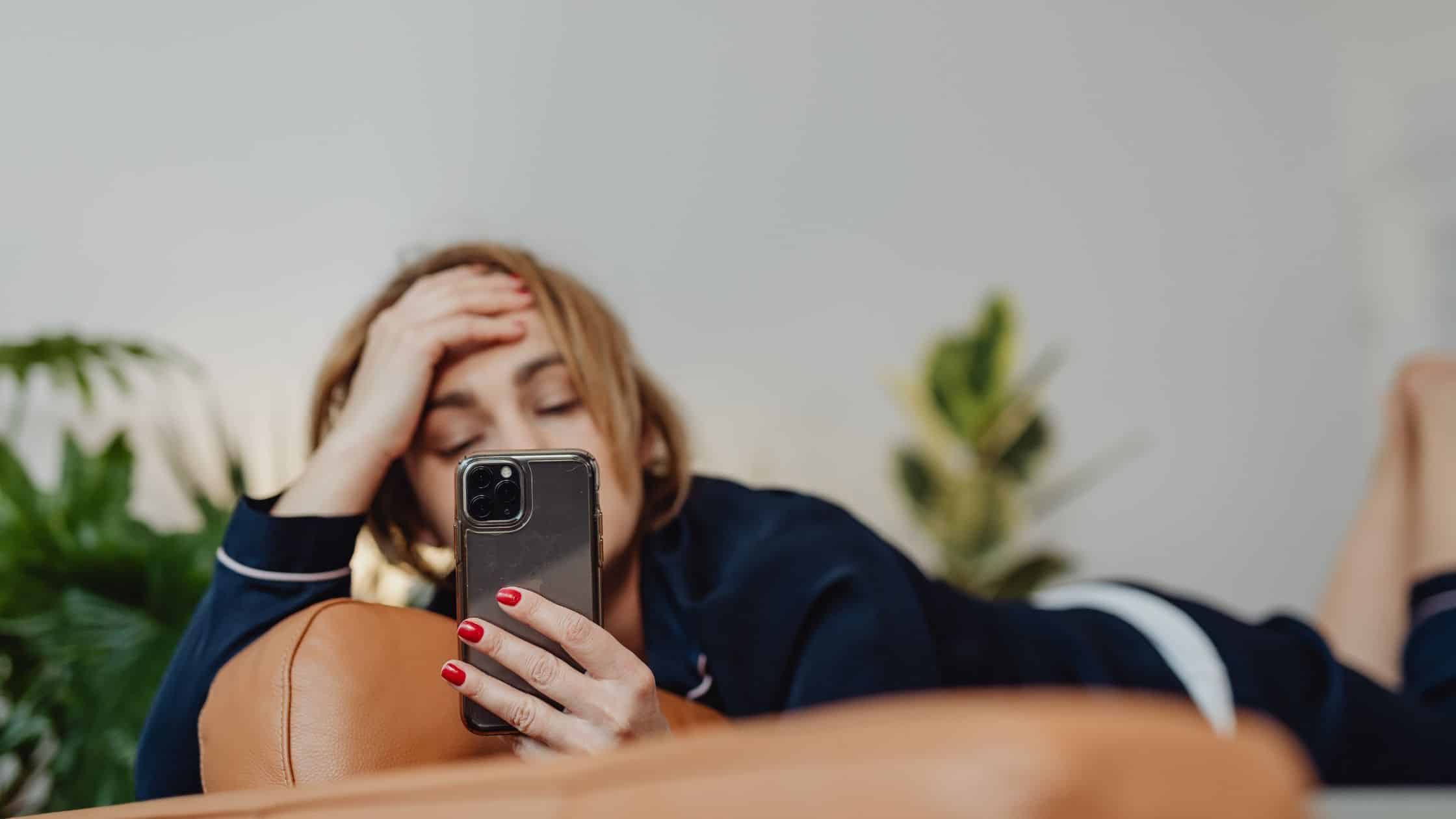 A woman lying down on a phone wondering "Why can't I tag a friend on Facebook"